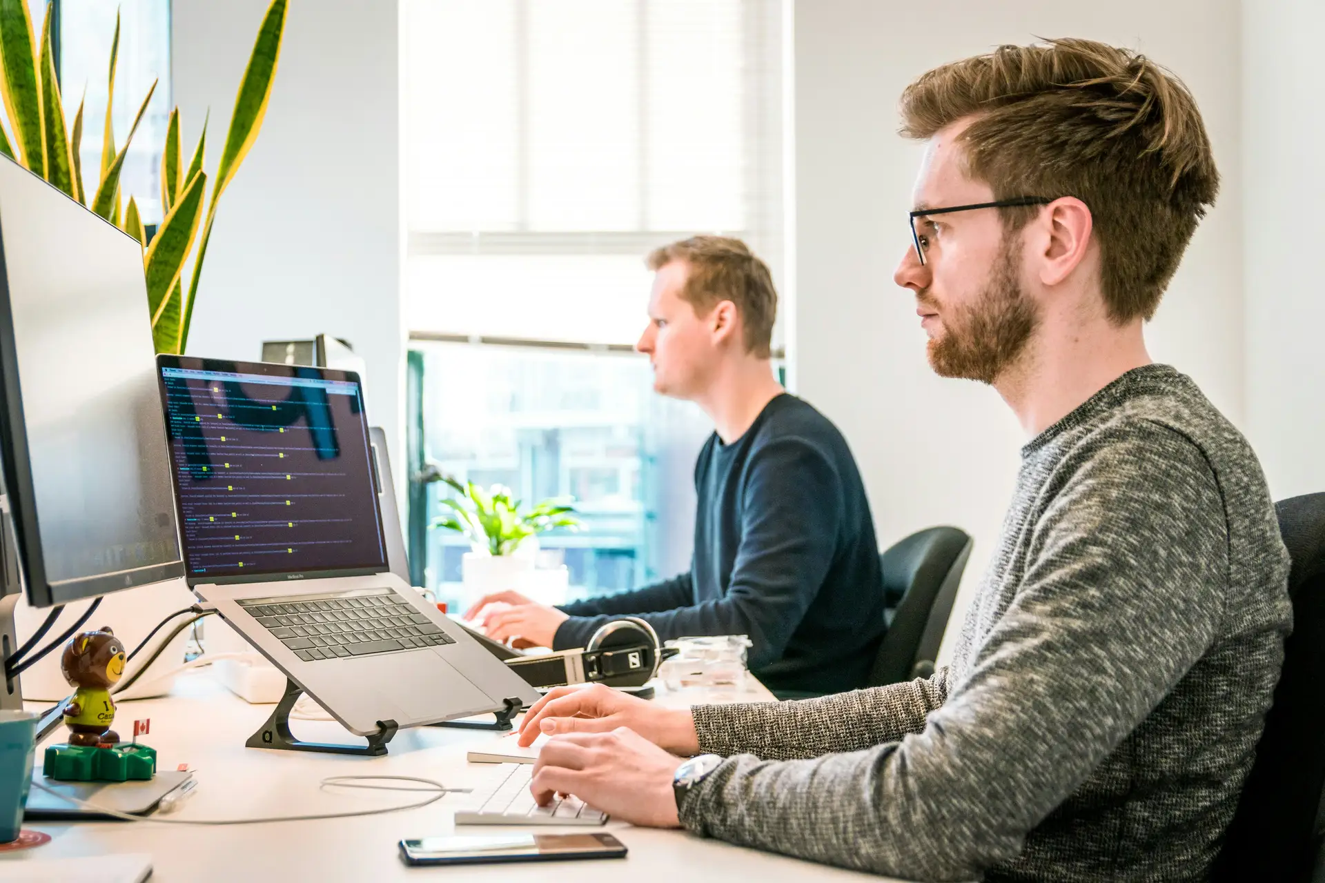 Person prüft konzentriert Textdokumente an zwei Monitoren