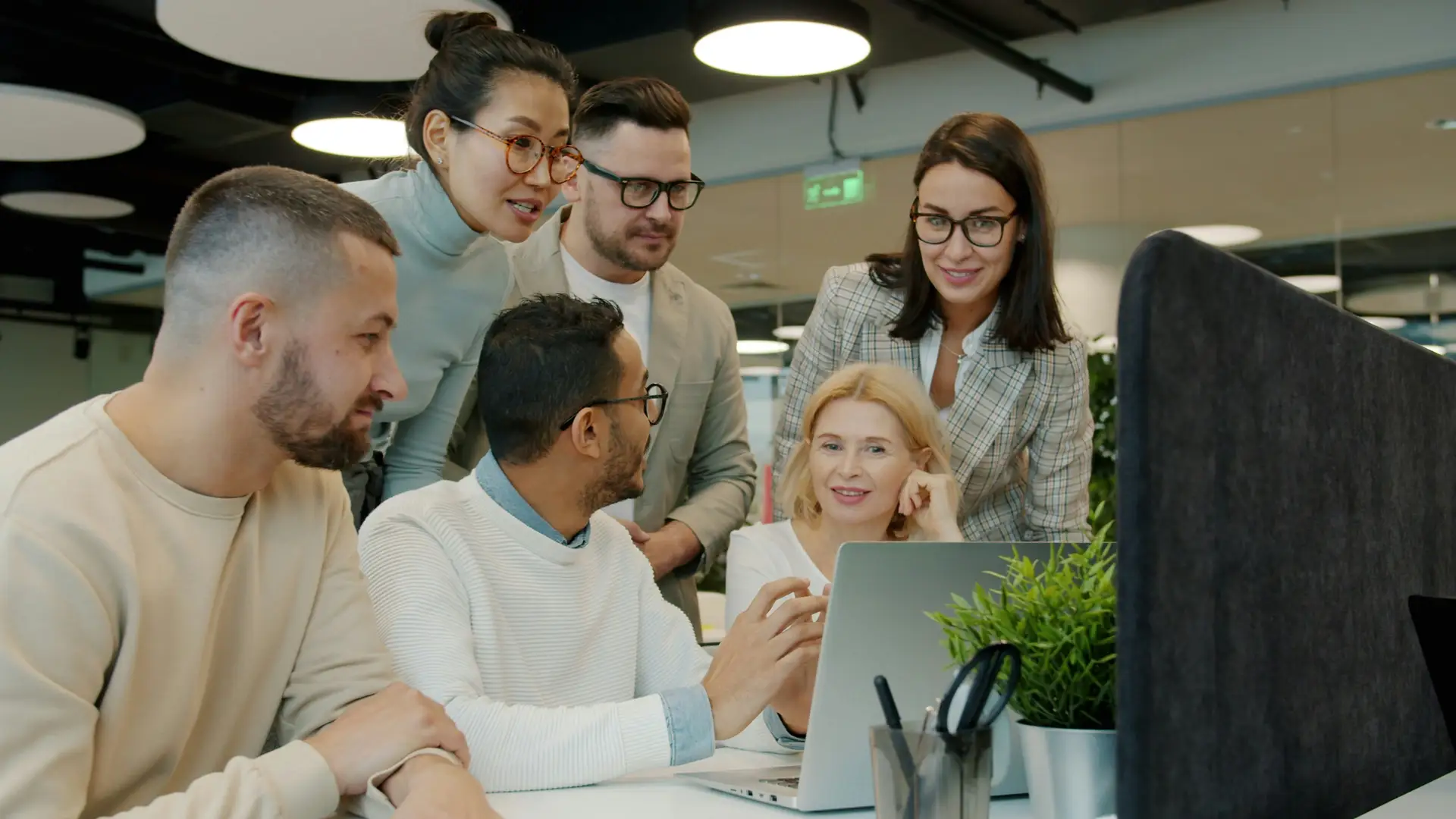 Team bespricht gemeinsam die Auswahl einer Übersetzungssoftware vor einem Bildschirm im Büro